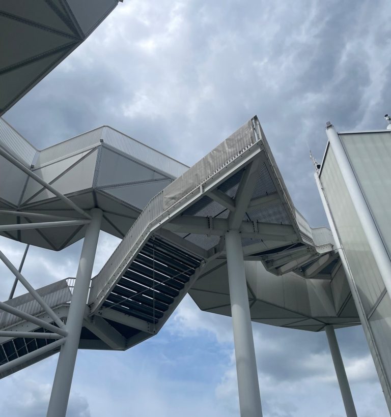 Blick auf die Seilbahn der Gärten der Welt, umgeben von Bäumen und bewölktem Himmel auf dem Kienberg.